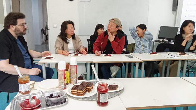 Adult learners discuss food and culture during a relaxed classroom conversation activity